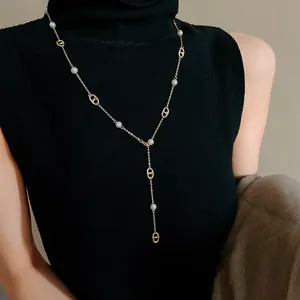 Detailed shot of a gold-plated pig nose link necklace with pearls on a black top