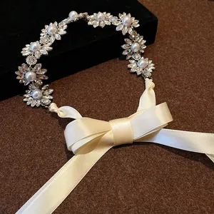Close-up of vintage rhinestone flower and pearl necklace with elegant cream ribbon bow