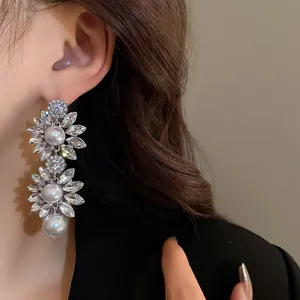 Close-up of vintage flower earrings with sparkling rhinestones and white pearls.