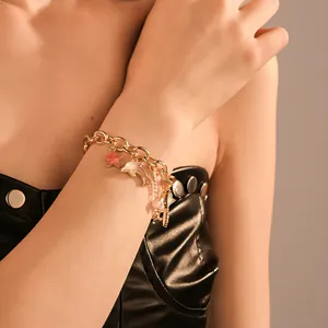 Close-up of ocean-themed gold charm bracelet with dolphin and starfish charms on female wrist
