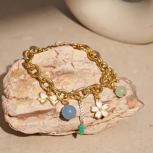 Detailed macro view of a gold chain charm bracelet featuring floral and bead accents