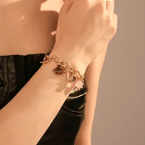 Detail view of a gold ocean charm bracelet with seashell and planet beads on a wrist