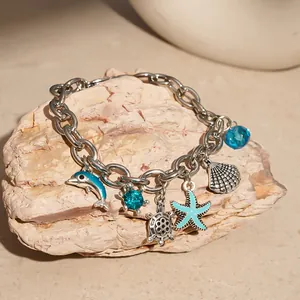 Detailed view of ocean-themed charm bracelet with enameled dolphin and starfish on a rock