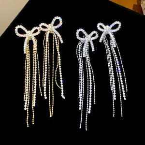 Close-up of elegant bow earrings with long rhinestone tassels in gold and silver finish.