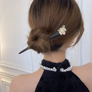 Vista dettagliata di un fermaglio per capelli a fiore vintage in uno chignon con abito nero.