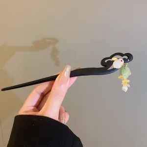 Dettaglio di fermaglio cinese in legno con coniglio bianco e nappe in finta giada