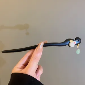 Dettaglio di un fermacapelli in legno nero con ornamento a coniglio bianco e perla verde