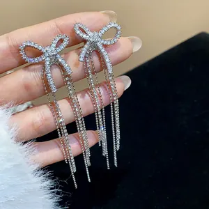 Detail view of elegant 18k gold plated zircon bow earrings with long dangling tassels.