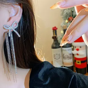 Close-up of elegant bow tassel earrings with sparkling crystals on a model's ear