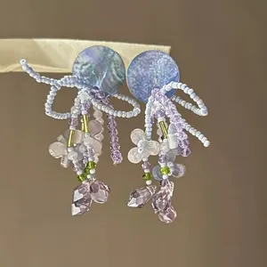 Close-up detail of handmade beaded flower tassel earrings with blue iridescent discs