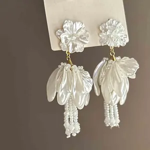 Primer plano de pendientes de flores blancas con pétalos nacarados y cuentas finas