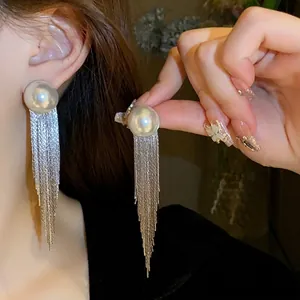 Long silver needle earrings with large half-round pearls and cascading metal chain tassels
