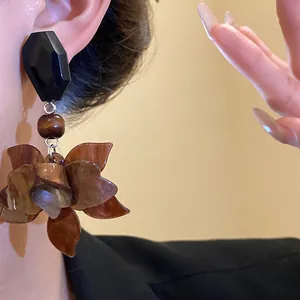 Close-up of retro Maillard resin flower drop earrings with black faceted bead detail