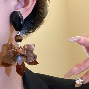 Close-up of vintage brown resin flower drop earrings with black geometric stud.