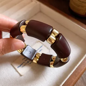 Primer plano detallado de una pulsera de acrílico burdeos con espaciadores dorados brillantes