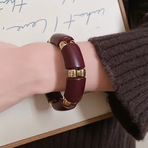 Primer plano de una pulsera de acrílico granate con espaciadores de metal dorado