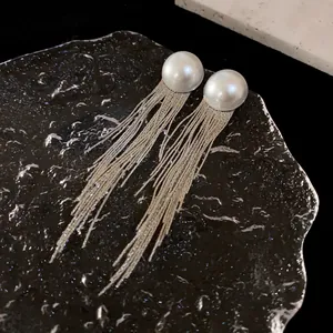 Detailed macro shot showcasing long silver tassel earrings with large elegant pearls.