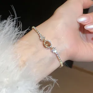 Elegante bracciale placcato oro con zircone champagne ovale indossato con polsino piumato