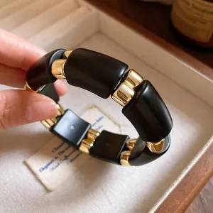 Primer plano de los detalles en negro mate y dorado de esta pulsera de diseño en acrílico