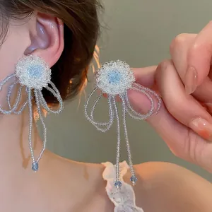 Primer plano de pendientes de flores de perlas hechos a mano con borlas y cristal