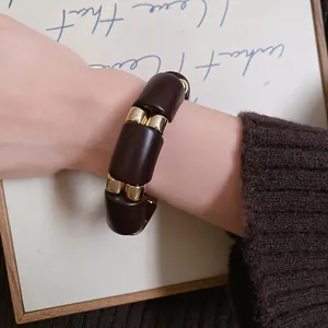 Detalle de una pulsera minimalista de acrílico marmoleado y oro empalmado en una muñeca