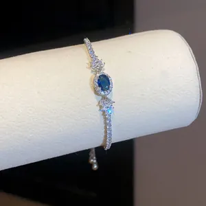Dettaglio di un elegante bracciale con zircone blu ovale e accenti scintillanti.