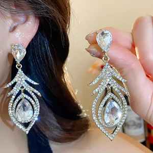 Macro view of vintage gold feather earrings featuring sparkling crystal teardrop inlays