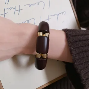 Primer plano de una pulsera minimalista segmentada de acrílico y tono dorado.