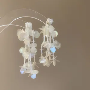 Primer plano de pendientes de borla de flores con lentejuelas irisadas en un soporte.