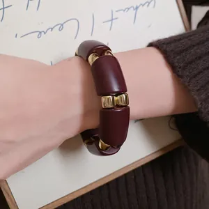 Primer plano de una pulsera de acrílico granate con espaciadores dorados en la muñeca