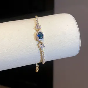 Vista dettagliata di un elegante bracciale in oro con zircone blu ovale e cristalli