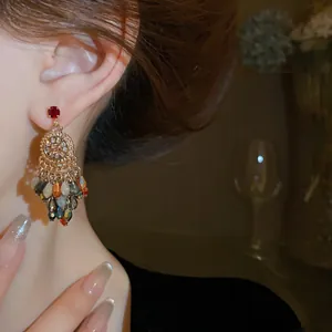 Close-up of elegant crystal tassel earrings worn on ear in warm low lighting conditions