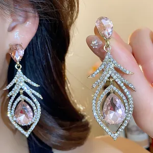 Macro view of vintage luxury feather earrings featuring pink teardrop gemstones and crystals
