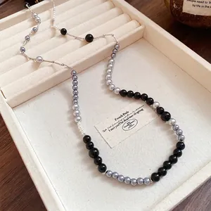 Vintage acrylic pearl necklace featuring grey and black beads displayed in a beige jewelry tray.