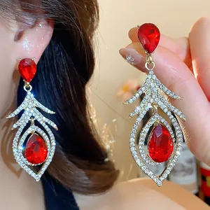 Macro detail of silver feather earrings with sparkling rhinestones and red gems