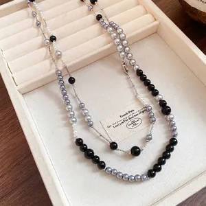 Vintage acrylic pearl necklace with grey and black beads on a beige jewelry tray