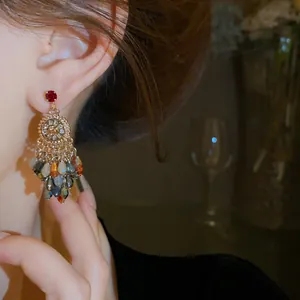 Close-up of crystal tassel earrings with sparkling flower and red stone detail