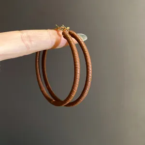 Detailed view of elegant brown leather-wrapped hoop earrings with silver needles