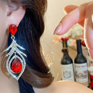 Detailed shot of vintage feather drop earrings with sparkling red gemstones and crystals.