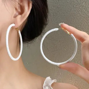 Detail of white leather-wrapped hoop earrings showcasing textured circular design.