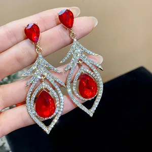 Detailed view of retro court style hollow feather earrings with red teardrop stones