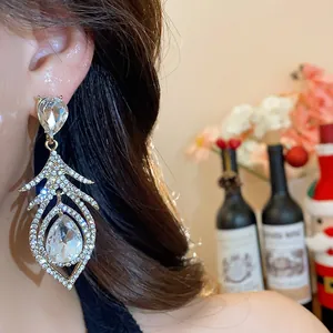 Close-up view of elegant rhinestone feather dangle earrings on a beautiful model's ear