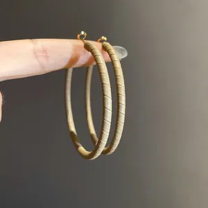 Detail shot of minimalist leather-wrapped hoop earrings with premium textured finish.