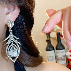 Detailed view of luxury silver needle hollow feather earrings encrusted with crystals.