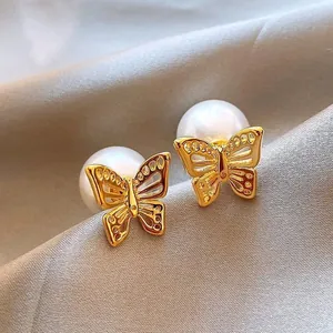 Primer plano de elegantes pendientes de mariposa bañados en oro con cierres de perlas grandes