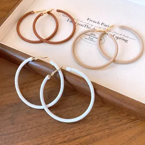 Detailed view of leather-wrapped hoop earrings in brown, beige, and white colors