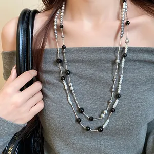 Detailed view of a long double-layered necklace featuring grey, black, and white pearls