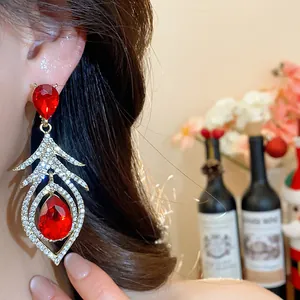 Detailed close-up of vintage red crystal feather-shaped drop earrings worn by a model