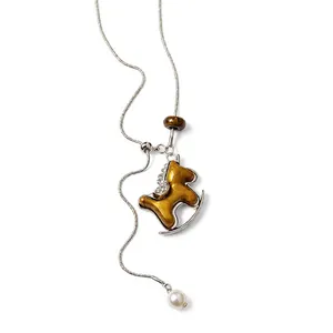 Elegante silberne Halskette mit goldenem Schaukelpferd-Anhänger und weißer Perle.