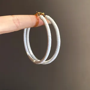 Macro view showing the fine texture of white leather wrapped elegant hoop earrings